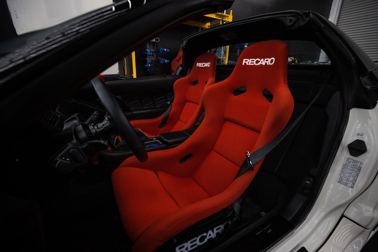Explore the luxurious interior with vibrant red Recaro seats, exuding elegance and style in a modern car setting.